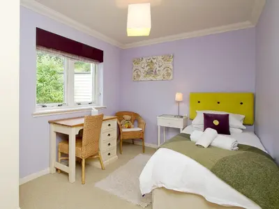 a bedroom with a bed and a desk and window at Carness West in North Ballachulish