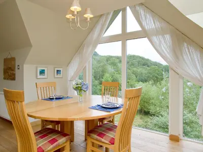 a dining room with a table and a large window at Carness West in North Ballachulish