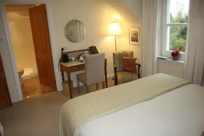 a bedroom with a bed and a desk and a table at Balmillig B&B in Helensburgh