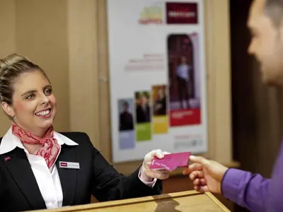a woman is handing a person a pink card at Mercure Ayr Hotel in Ayr