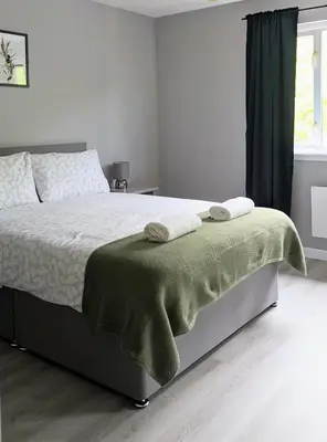 a bedroom with a bed with a green blanket on it at Campbeltown View in Campbeltown