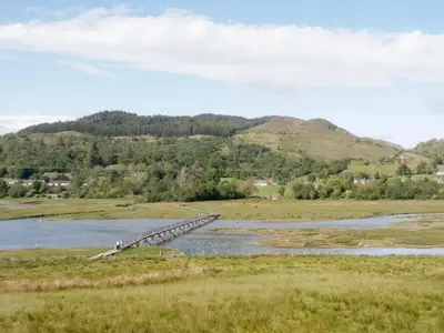 a wooden bridge over a river in a field at Glenview in Appin
