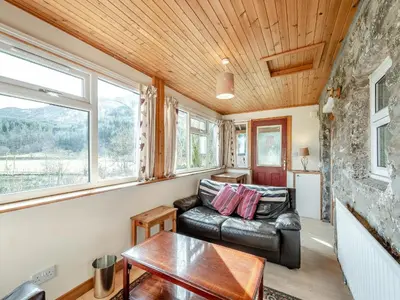 a living room with a leather couch and a table at Stonefield Farm Cottage in Benmore