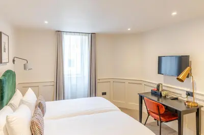 a hotel room with a bed and a desk and a tv at Grove House Hotel in Edinburgh