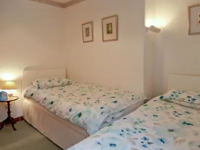 a bedroom with two beds and a table with a lamp at 15 Cairnbaan Cottage in Cairnbaan