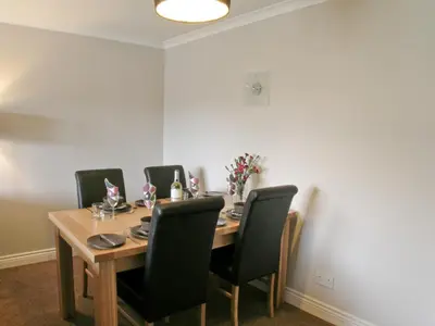a dining room with a wooden table and black chairs at Kerrera View in Oban