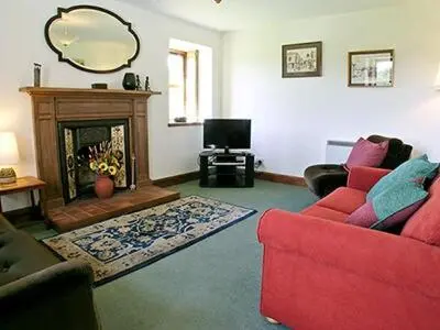 a living room with a red couch and a fireplace at Dalvuie Beag in Connel