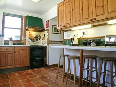 a kitchen with wooden cabinets and bar stools at Dalvuie Beag in Connel