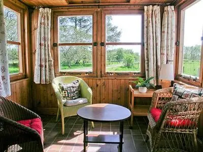 a living room with chairs and a table and windows at Dalvuie Beag in Connel