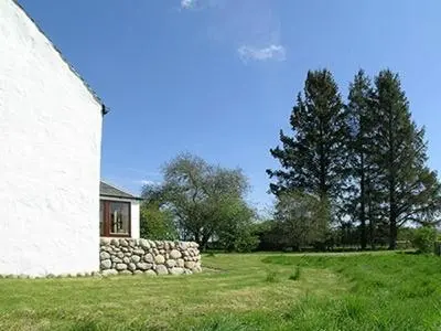 a house with a stone wall next to a building at Dalvuie Beag in Connel