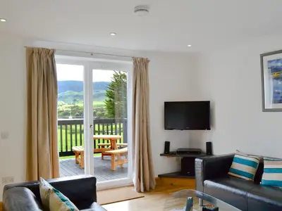 a living room with a couch and a television and a balcony at Lunga - 28791 in Clachan