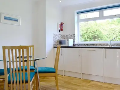 a kitchen with white cabinets and a table and a window at Lunga - 28791 in Clachan