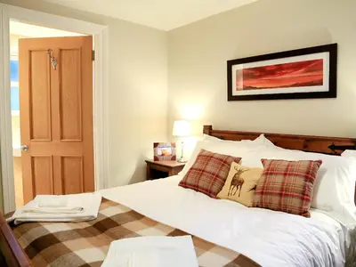 a bedroom with a white bed with a plaid blanket at Ardbhan Croft in Oban