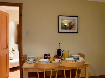 a wooden table with chairs and a table with food on it at Inn Cottage in Glendevon