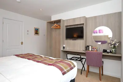a bedroom with a bed and a desk and a tv at Fyne Rooms in Tighnabruaich