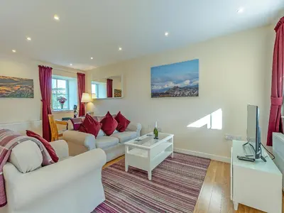 a living room with white furniture and red pillows at Kestrel Cottage - 27937 in Stirling