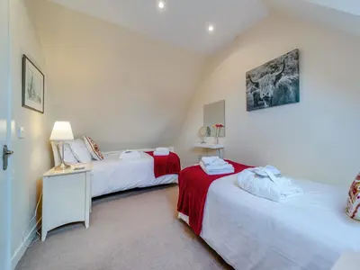 a room with two beds and a table with a lamp at Peregrine Cottage in Stirling
