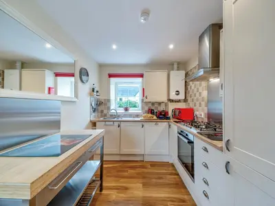 a kitchen with white cabinets and a counter top at Peregrine Cottage in Stirling
