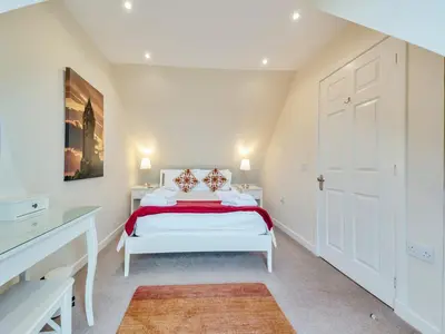 a white bedroom with a white bed with red sheets at Peregrine Cottage in Stirling