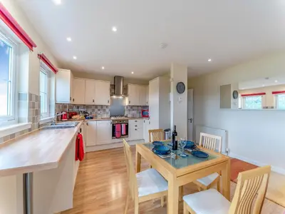 a kitchen and dining room with a wooden table and chairs at Osprey Cottage- 27939 in Stirling