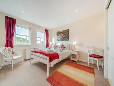 a bedroom with a bed and a chair and windows at Buzzard Cottage - 27940 in Stirling