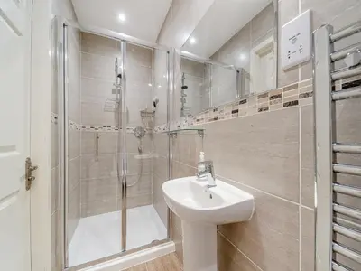 a white bathroom with a shower and a sink at Buzzard Cottage - 27940 in Stirling