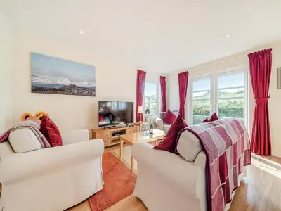 a living room with two white chairs and a tv at Buzzard Cottage - 27940 in Stirling