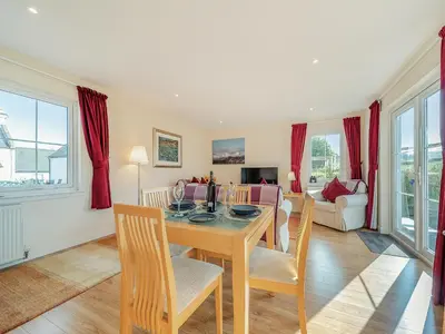 a dining room and living room with a table and chairs at Buzzard Cottage - 27940 in Stirling
