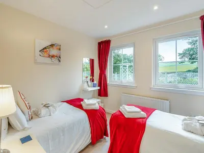 two beds in a bedroom with red curtains at Barn Owl Cottage - 27941 in Stirling