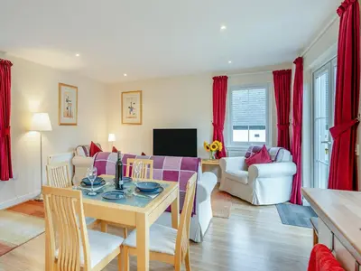 a dining room and living room with red curtains at Barn Owl Cottage - 27941 in Stirling