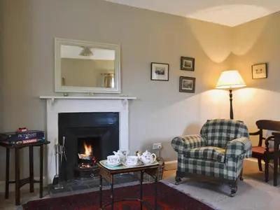 a living room with a fireplace and a chair and a mirror at Old Inzievar in Blairhall