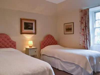 two beds in a room with a window at Old Inzievar in Blairhall