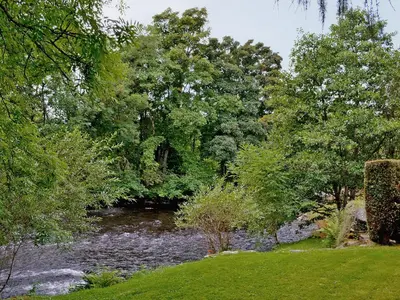 a river in the middle of a park with trees at Rathlin Coach House in Comrie