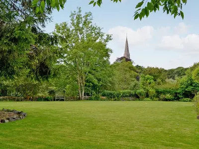 a large grass field with a church in the background at Rathlin Coach House in Comrie