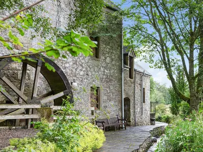 an old stone house with a wooden gate and benches at Fochy Cottage in Milnathort