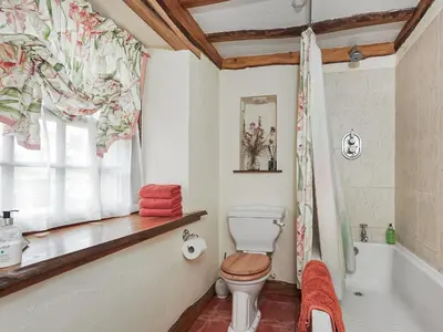 a bathroom with a toilet and a tub and a window at The Hayloft in Milnathort