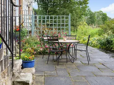 a patio with a table and chairs and flowers at The Hayloft in Milnathort