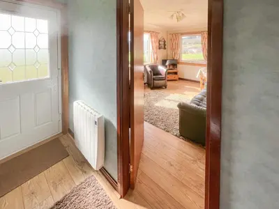 a hallway with a door leading to a living room at Gean Cottage in Powmill