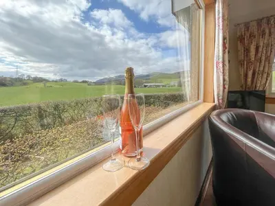 a bottle of wine and two glasses sitting on a window at Gean Cottage in Powmill