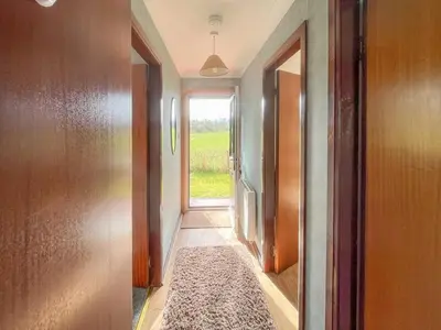 an empty hallway with a door and a window at Gean Cottage in Powmill
