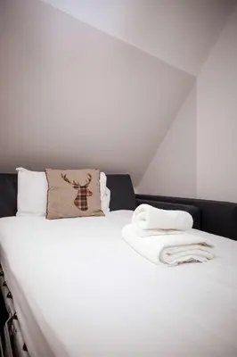 a white bed with a pillow and towels on it at Bruntsfield Hotel in Edinburgh