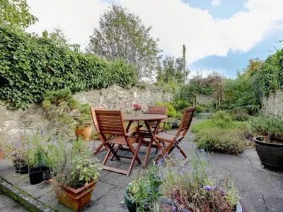 two chairs and a table in a garden with plants at Garden Cottage in Linlithgow