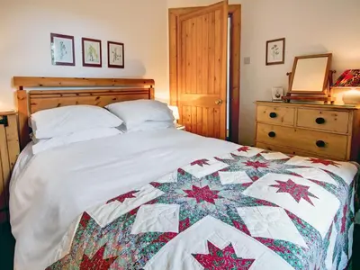 a bedroom with a bed with a quilt on it at Garden Cottage in Linlithgow