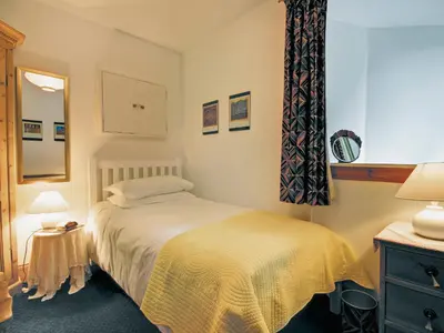 a small bedroom with a bed and a mirror at Garden Cottage in Linlithgow