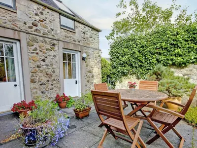 a patio with a wooden table and chairs at Garden Cottage in Linlithgow