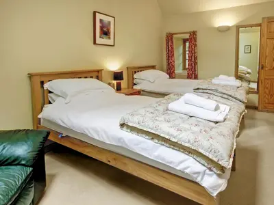 two twin beds in a bedroom with a couch at Coach House in Ratho