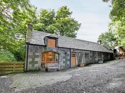 a stone house with a garage and a fence at Coach House in Ratho