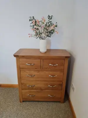 a vase of flowers sitting on top of a dresser at Kings Reach - Dunadd Cottage in Lochgilphead