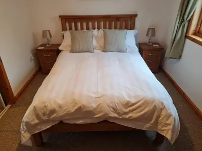 a bedroom with a large white bed with two night stands at Kings Reach - Dunadd Cottage in Lochgilphead