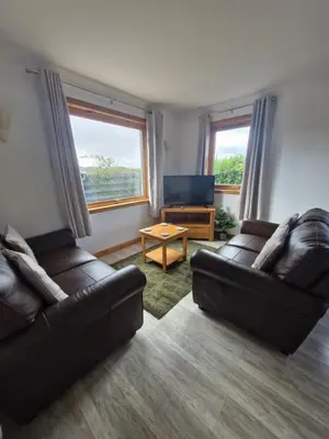 a living room with two leather couches and a television at Kings Reach - Dunadd Cottage in Lochgilphead